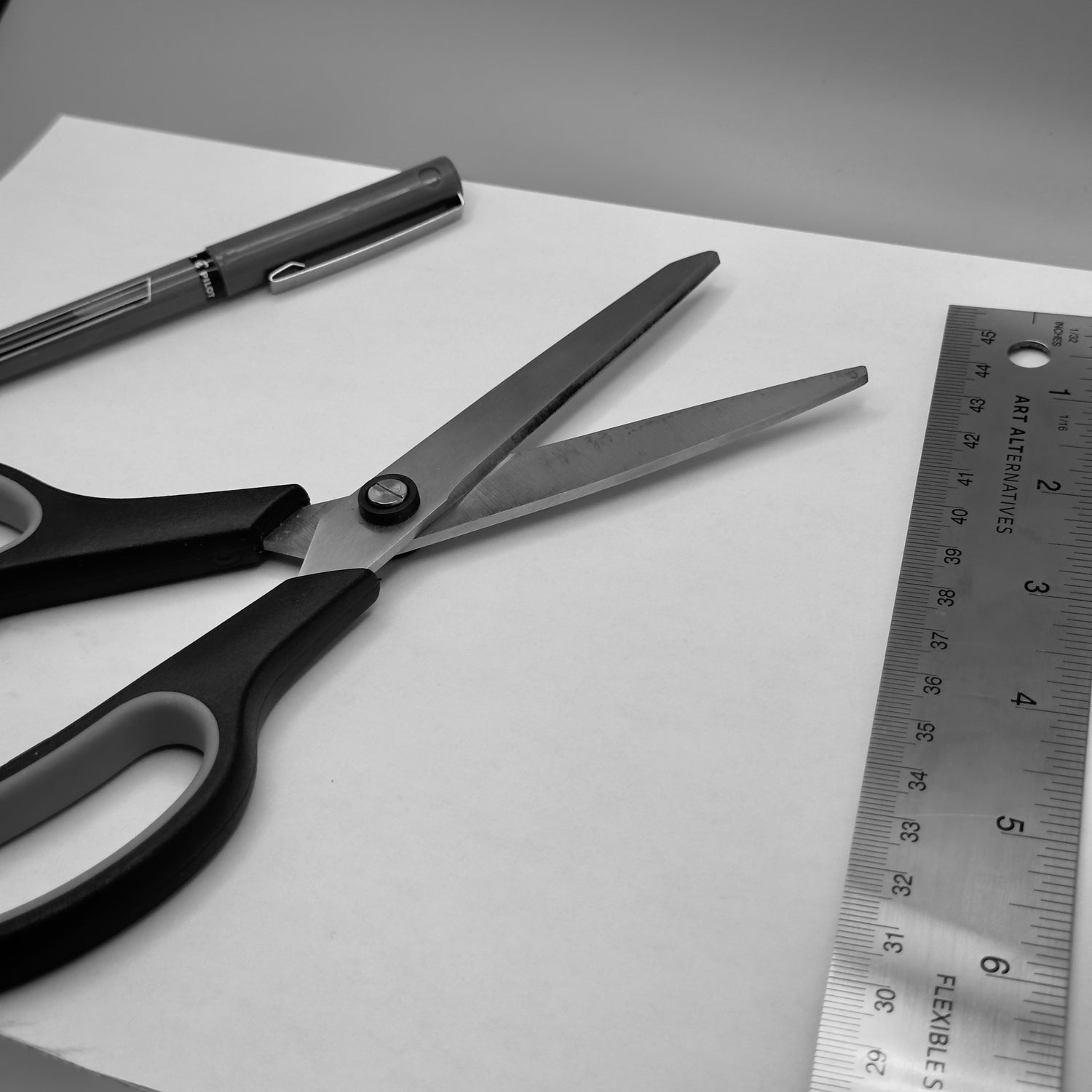 scissors, pen, paper, and ruler on a blank background