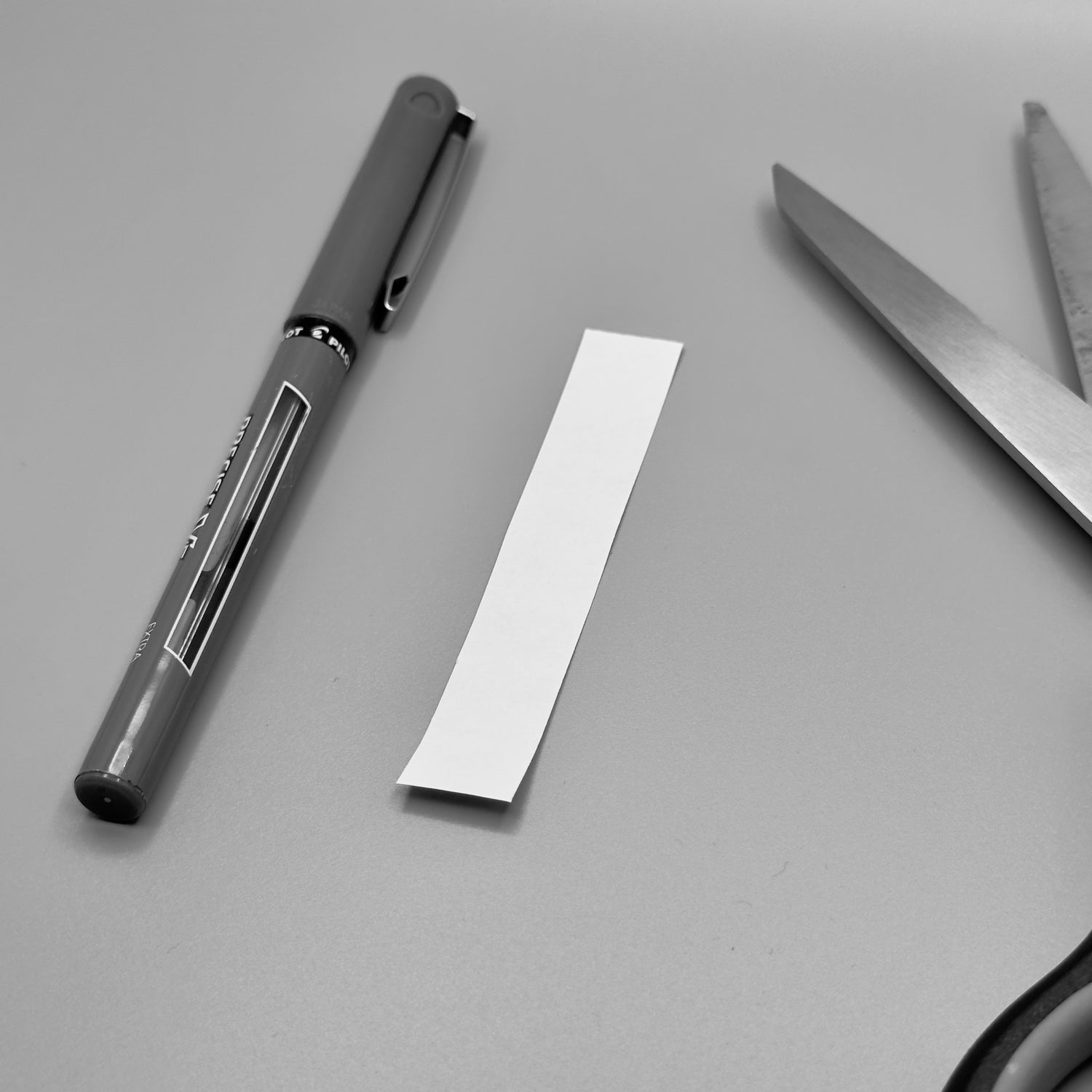 strip of paper next to a pen and scissors