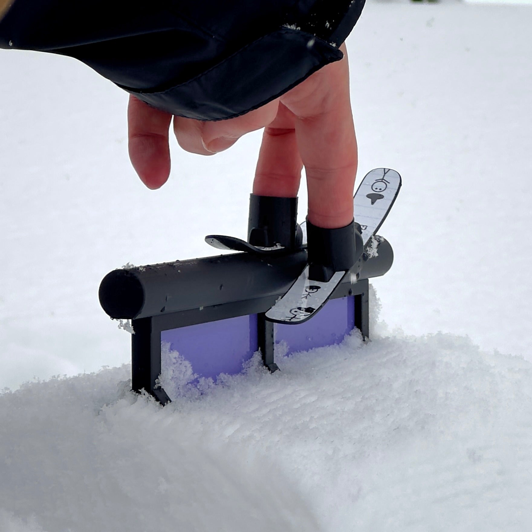 SlideofHand Finger Skis Doodle Graphic from behind on a walled tube rail being used in the snow