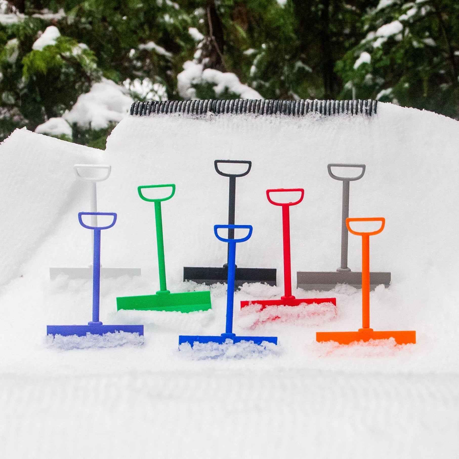 slideofhand park rakes in assorted colors sitting in the snow next to a tube rail feature