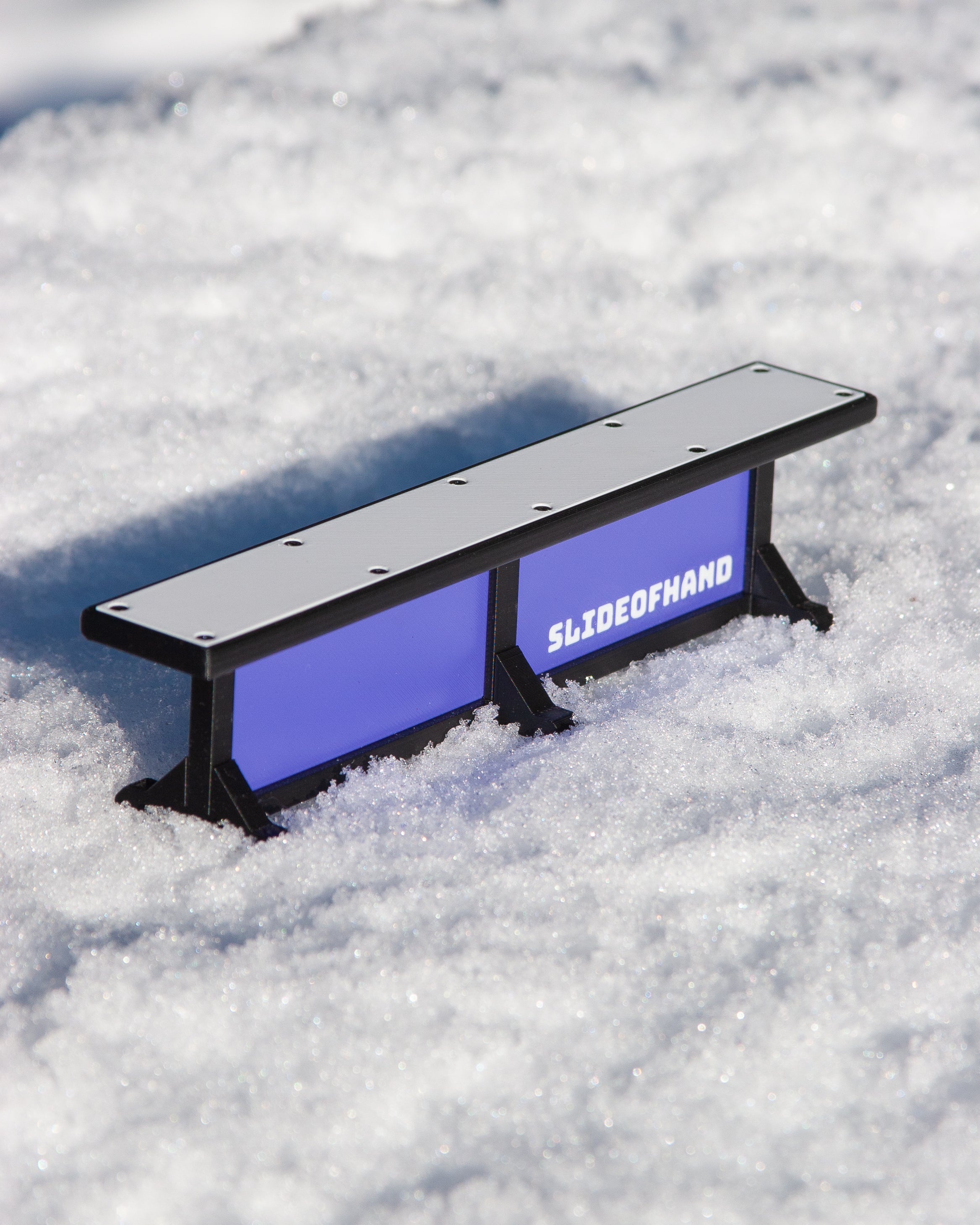 slideofhand finger ski terrain park box rail purple sitting on snow