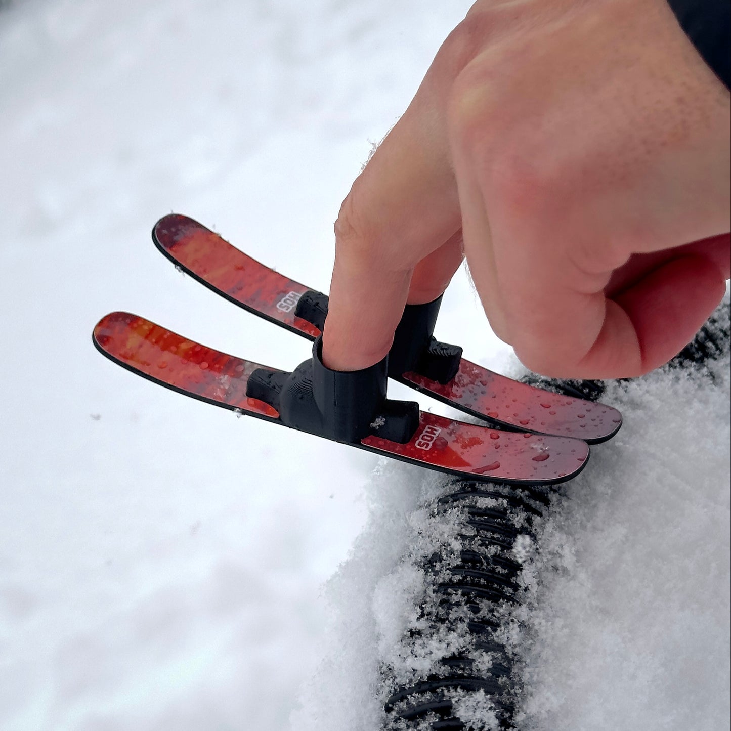 SlideofHand Finger Skis Sunrise Graphic being used by a persons hand on a corrugated rail feature in snow