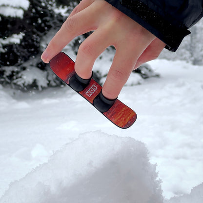 Jumping SlideofHand Finger Snowboard black with red sunrise graphic in snow